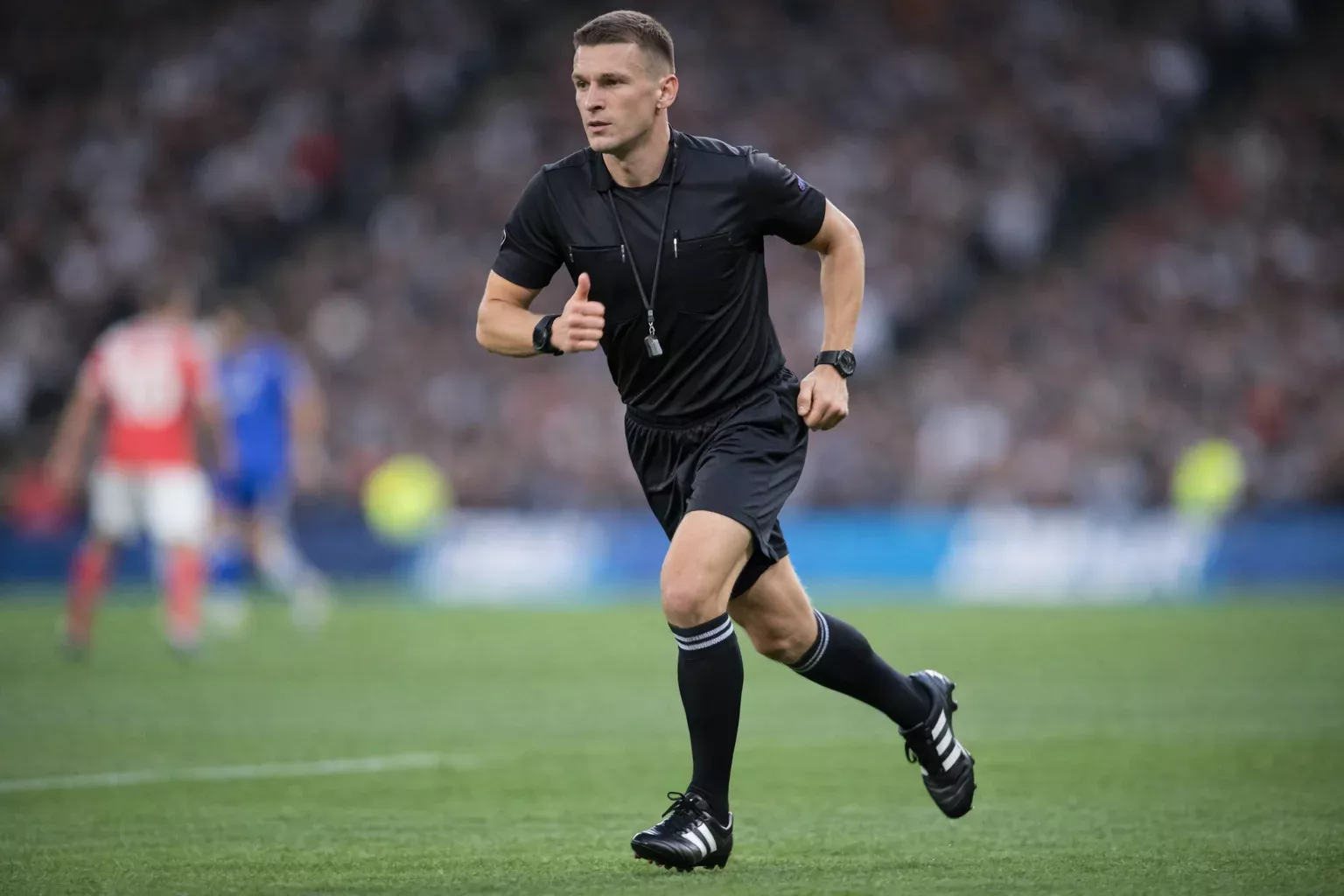 Árbitro de fútbol corriendo por el campo siguiendo el juego de cerca